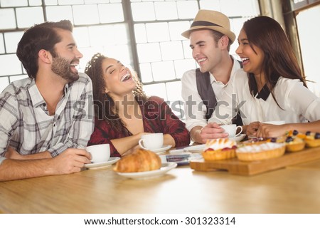 Laughing friends enjoying coffee and treats at coffee shop