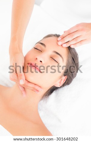 Side view of an attractive young woman receiving head massage at spa center