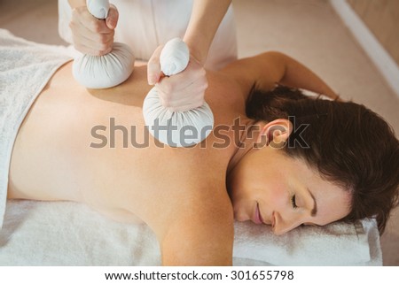 Young woman getting herbal compress massage in therapy room