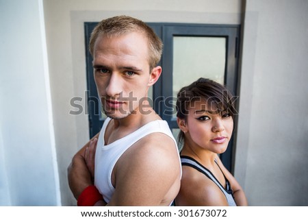 Portrait of extreme athletes standing back to back with arms crossed in front of a building
