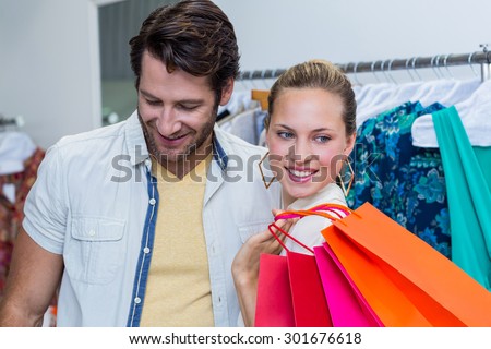 Smiling couple standing next to clothes rail in clothing store