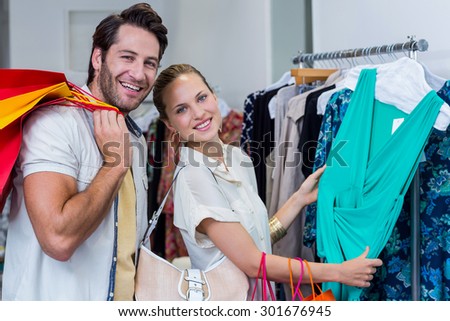 Portrait of smiling couple browsing clothes in clothing store