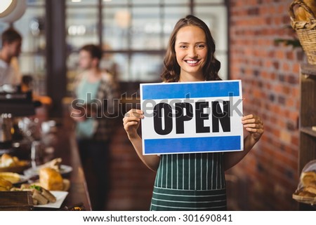 Portrait of a waitress posing with open sign at the coffee shop