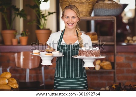 Waitress holding a chocolate cake and cupcakes at the coffee shop