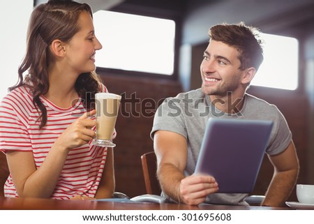 Smiling friends looking at each other at coffee shop
