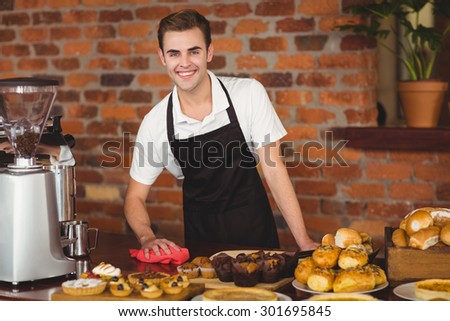 Portrait of smiling barista cleaning the counter at coffee shop