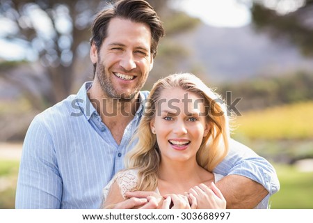 Portrait of a standing cute couple with arms around