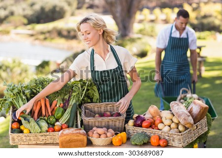 Farmer woman tidying up a table of local food at the local market
