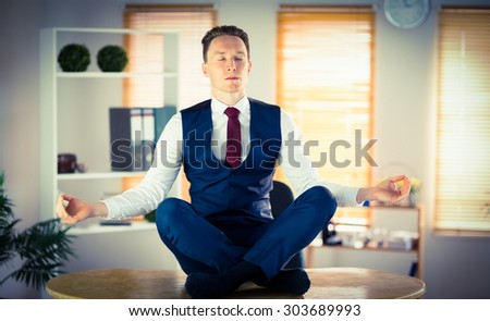 Calm businessman meditating in lotus pose in his office