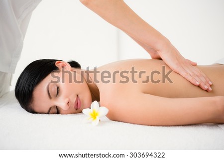 Pretty brunette enjoying a massage with flower at health spa