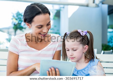 Mother and daughter using tablet computer together in a restaurant