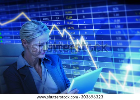 Businesswoman using tablet against stocks and shares
