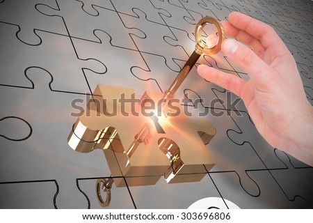 Businessman in suit holding his hand out against key unlocking jigsaw