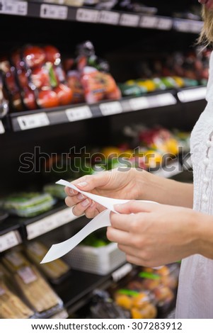 A woman looking at her grocery list in the supermarket