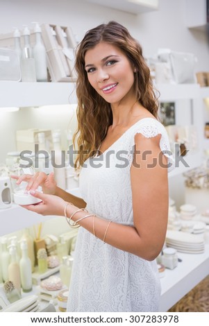 Portrait of smiling woman testing moisturizer and looking at camera at a beauty salon