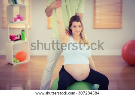 Pregnant woman having relaxing massage while sitting on exercise ball in a studio
