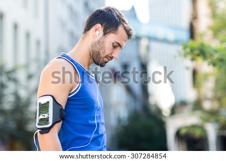 An handsome athlete listening to music on a sunny day