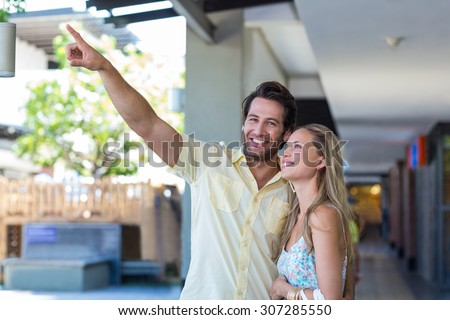 Portrait of smiling couple looking and pointing at shopping mall