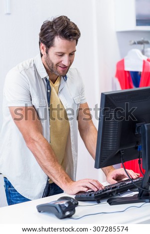 Smiling cashier typing in clothing store