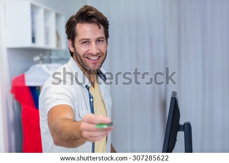 Portrait of smiling cashier handing back credit card in clothing store