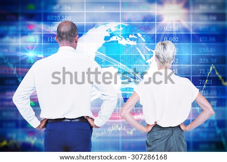 Smiling business people with hands on the hips against stocks and shares Smiling business people back to the camera with hands on the hips