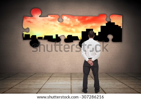 Businessman turning his back to camera against cityscape stencil on red sky