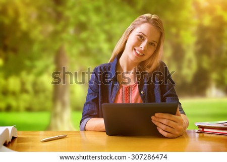 Student studying in the library with tablet against trees and meadow