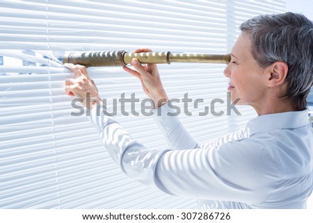 Side view of businesswoman looking through field-glass in the office