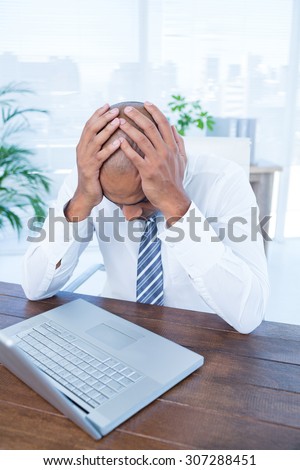 Anxious businessman with head in hands at office