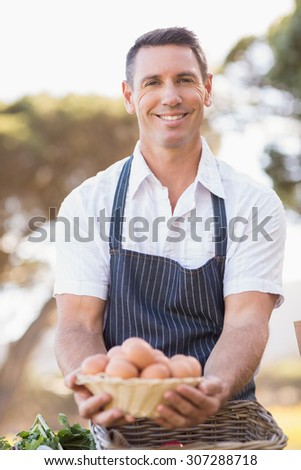 Portrait of a smiling farmer holding a basket of eggs