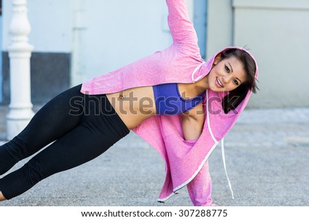Portrait of athletic woman exercising side plank in the city