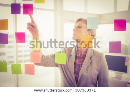Casual businesswoman reading sticky notes in the office
