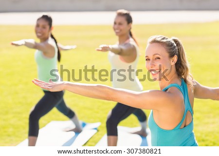 Portrait of yoga teacher and sporty women attending yoga class in parkland