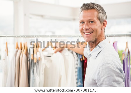 Portrait of smiling man browsing clothes in clothing store