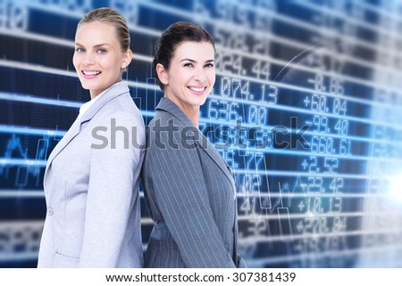 Attractive businesswomen standing back-to-back against stocks and shares