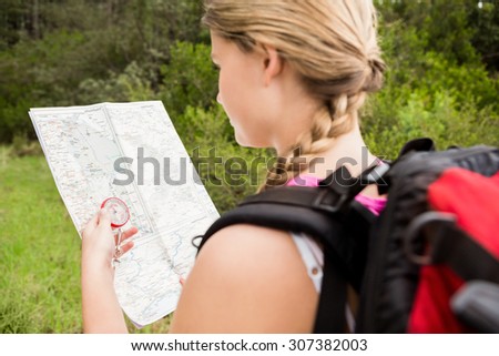 Blonde hiker with compass and reading map in the nature