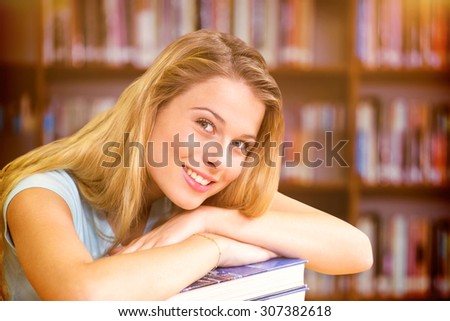 Portrait of female student in library against books on desk in library