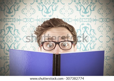 Geeky student reading a book against elegant patterned wallpaper in blue and cream