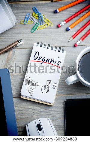 The word organic and business graphs against notepad on desk