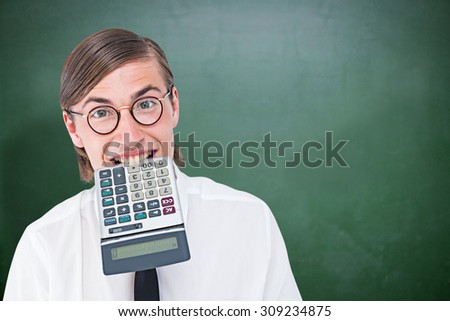 Geeky smiling businessman biting calculator against green chalkboard