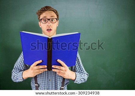 Geeky businessman holding a book against green chalkboard