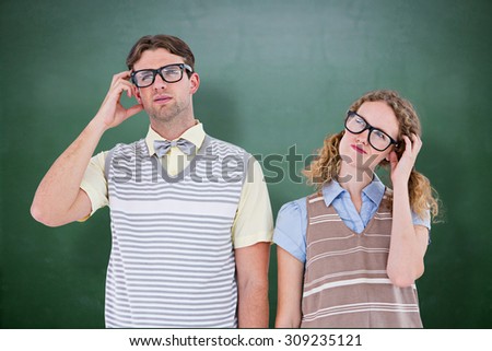 Geeky hipster couple thinking with hand on temple against green chalkboard
