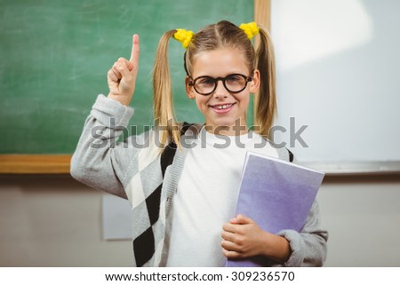 Portrait of cute pupil holding books in a classroom in school
