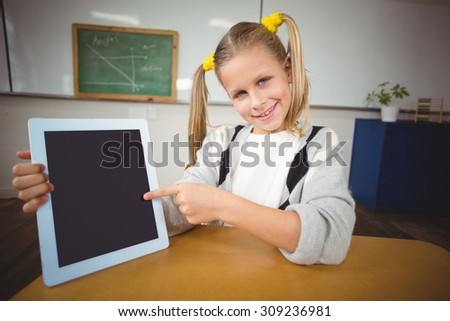 Portrait of smiling pupil pointing on tablet in a classroom in school