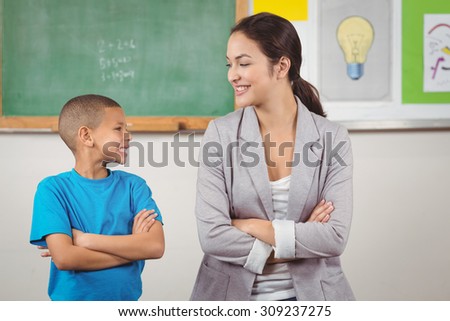 Pretty teacher and cute pupil in front of chalkboard in a classroom