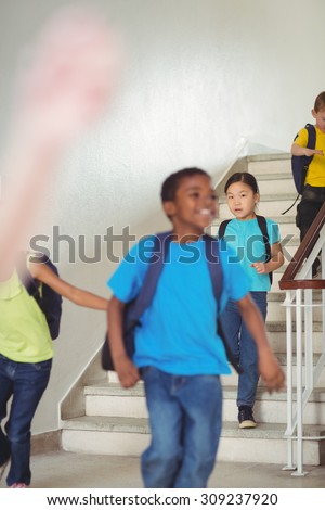 Happy pupils walking down the stairs in school