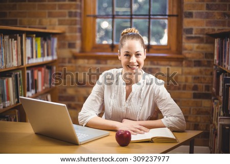 Portrait of blonde teacher reading book in the library in school