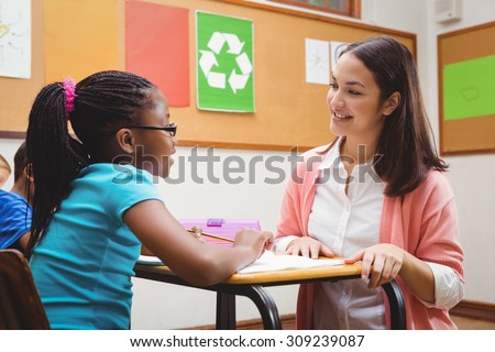 Happy teacher helping her students at the elementary school
