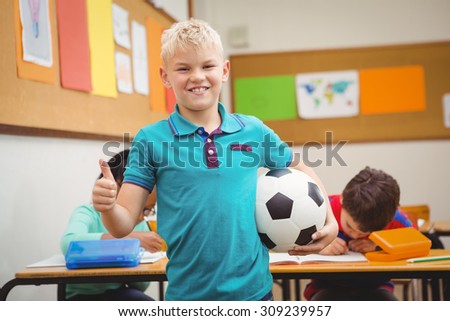 Smiling student holding a football at the elementary school