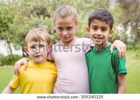 Happy children standing together with arms around each other outside